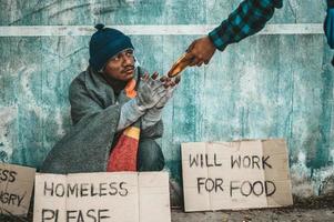 Die Brotmacher geben einem Bettler am Straßenrand foto