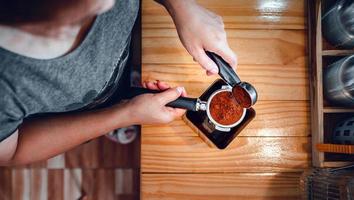 barista gießt kaffeebohnenrösterpulver gemahlenen kaffee, der mit einer barista-hand im café in einen portafilter gegossen wird foto