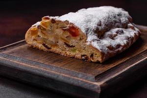 weihnachtstortenstollen mit marzipan, beeren und nüssen auf dunklem betonhintergrund foto