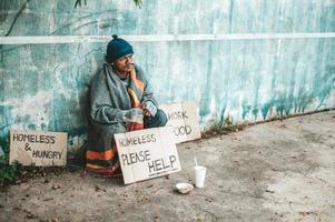 Mann sitzt neben der Straße mit einer obdachlosen Nachricht foto