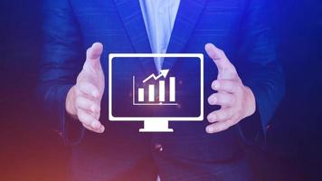 geschäftsmann, der geschäftswachstum auf diagramm zeigt, hände, die diagramme berühren, die steigende gewinne mit virtueller schnittstellentechnologie darstellen, kommende finanzsymbole foto