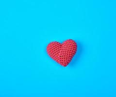 klein rot gestrickt Herz auf ein Blau Hintergrund foto