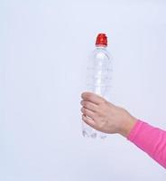 transparente Plastikflasche mit frischem Wasser in einer weiblichen Hand foto