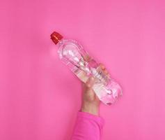 transparente Plastikflasche mit frischem Wasser in einer weiblichen Hand foto