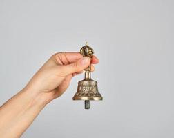 weiblich Hand halten ein Bronze- Glocke zum Alternative Medizin foto