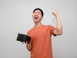 positiv Mann Orange gestreift Hemd halten Brieftasche glücklich mit verdienen Geld, reich Mann halten Brieftasche fühlt sich Erfolg foto