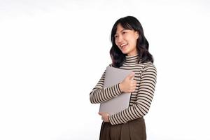 schön jung asiatisch Frau auf Sweatshirt Kleidung halten Laptop pc Computer und suchen beim Kamera mit Lächeln Gesicht, isoliert auf Weiß Hintergrund