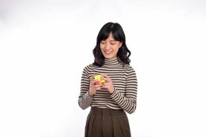 asiatisch Frau halten ein rubik Würfel Stehen auf Weiß Hintergrund. lösen kubisch Probleme, Problem Lösung und Herstellung strategisch bewegt sich Konzept foto