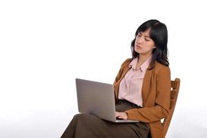 verärgert jung Geschäft asiatisch Frau. während ihr mit Laptop Sitzung auf hölzern Stuhl isolieren auf Weiß Hintergrund foto