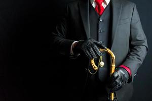Porträt von Gentleman im schwarz passen und Leder Handschuhe halten Regenschirm auf schwarz Hintergrund. Kopieren Raum zum Jahrgang Mode und retro Stil. foto