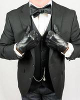 Porträt von schick Gentleman im schwarz passen und Leder Handschuhe. Jahrgang Mode und retro Stil. elegant Gentleman im Abend Kleid. foto