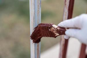 Hand hält ein Pinsel und Farben das Zaun, Reparatur. foto