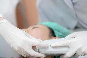 Kosmetikerin Verfahren durch elektrisch Gerät, Ultraschall Therapie Behandlung zum Haut festziehen im ästhetisch Klinik. foto