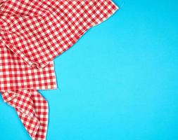 Weiß rot kariert Küche Handtuch auf ein Blau Hintergrund foto