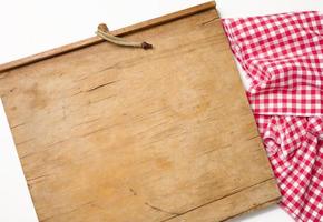 leeres rechteckiges Küchenschneidebrett aus Holz und rotes Handtuch in einem weißen Käfig auf einem weißen Tisch, Draufsicht foto