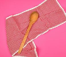 hölzern Löffel auf ein rot Küche Handtuch, Rosa Hintergrund foto
