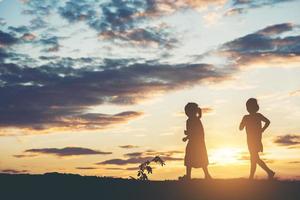 Sonnenuntergangssilhouette der spielenden Kinder foto