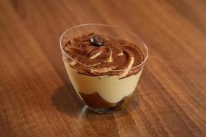 Tiramisu in Glas auf Vintage-Tisch, traditionelles italienisches Dessert mit Kaffeegeschmack aus Ladyfingern und Mascarpone foto