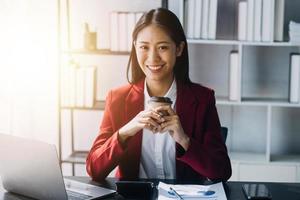 asiatische frauen sind gestresst, während sie am laptop arbeiten, müde asiatische geschäftsfrau mit kopfschmerzen im büro, sich bei der arbeit krank fühlen, kopierraum foto