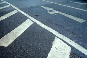 schließen oben Weiß Pfeil auf Asphalt Straße Hintergrund. foto