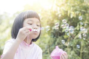 asiatisches Kind, das Blasen im Park bläst foto