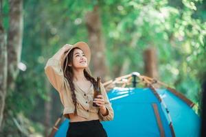 junge Frau jubelt und trinkt Getränke vor dem Campingzelt foto