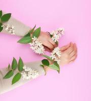 zwei weiblich Hände und klein Weiß Blumen foto