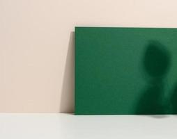 leer Grün Karton Blatt von Papier mit Schatten auf Weiß Tisch. Vorlage zum Flyer foto