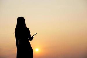 Silhouette von ein Frau halten ein Computer Sonnenuntergang Hintergrund foto