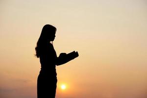 Silhouette von ein Frau halten ein Computer Sonnenuntergang Hintergrund foto