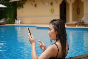 Online-Zahlung, ein Teenager-Mädchen, das schwimmt, benutzt ihr Smartphone mit ihrer Kreditkarte, um Einkäufe zu tätigen. online über das Internet. foto