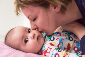 junge mutter, die ihr süßes kleines baby küsst foto