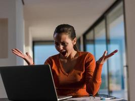 entspannte junge frau zu hause, die an laptop-computer arbeitet foto