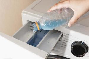 Nahaufnahme der Hand einer Frau, die Waschmittel in das Waschmaschinenfach gießt. foto