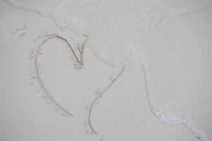 Herzen auf den Sand eines Strandes gezeichnet foto