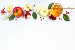 Konzept des traditionellen jüdischen Feiertags Rosch Haschana. Neujahr. Granatäpfel, Honig und Äpfel auf weißem Hintergrund. Platz für Ihren Text. foto