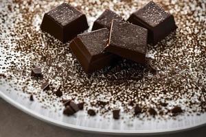 Schokolade Stück und Zucker Pulver Belag auf das Weiß Platte. foto