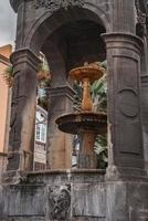 Brunnen mit mittelalterlich Struktur gesehen durch Bogen beim Platz del espiritu Santo foto