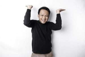 aufgeregt asiatisch Mann tragen schwarz Hemd zeigen beim das Kopieren Raum auf oben von ihn, isoliert durch Weiß Hintergrund foto