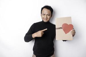 schön jung asiatisch Mann tragen schwarz Hemd halten Geschenk Box rot Herz, Valentinstag Tag Konzept. foto