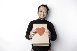 schön jung asiatisch Mann tragen schwarz Hemd halten Geschenk Box rot Herz, Valentinstag Tag Konzept. foto