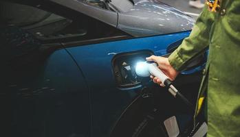 Mann verbinden ein Laden Kabel zu ein Auto von ein elektrisch Auto Laden Bahnhof. foto