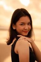 ein asiatisch Teenager Frau mit ein schwarz Hemd und schwarz Haar hat ein süß Gesicht wann sie lächelt und genießt das Aussicht foto