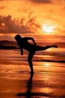 Silhouette von ein asiatisch Frau Tanzen Ballett mit großartig Flexibilität und ein Aussicht von das Wellen hinter ihr foto