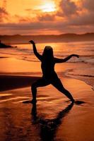 Silhouette Bild von ein asiatisch Frau tun Ballett Bewegungen sehr flexibel auf das Strand foto