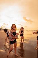 ein Gruppe von asiatisch Jugendliche Laufen mit glücklich Ausdrücke auf Ferien mit ihr freunde betrunken auf das Strand foto
