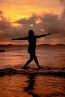 Silhouette von ein asiatisch Frau spielen im das Wasser auf das Strand mit stark Wellen abstürzen foto