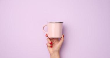 weiblich Hand halten ein Rosa Keramik Becher auf ein lila Hintergrund, brechen Zeit und trinken Kaffee, Banner foto
