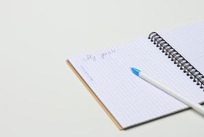 Öffnen Sie ein leeres Notizbuch mit Stift auf einem weißen Tisch foto