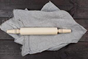 hölzern rollen Stift auf ein grau Leinen- Serviette foto